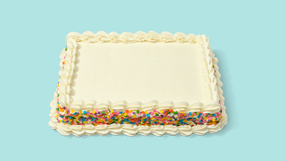 Large square cake with white frosting and multicolored sprinkles on top, placed on a blue surface.