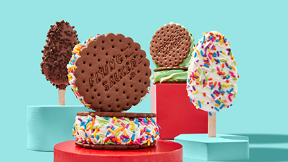 A vibrant and colorful display of cookie dough pops on skewers and donuts, each creatively decorated and presented in three stacks, suggesting a festive or celebratory event.